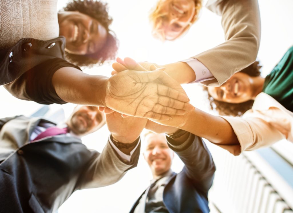 Equipo diverso uniendo sus manos