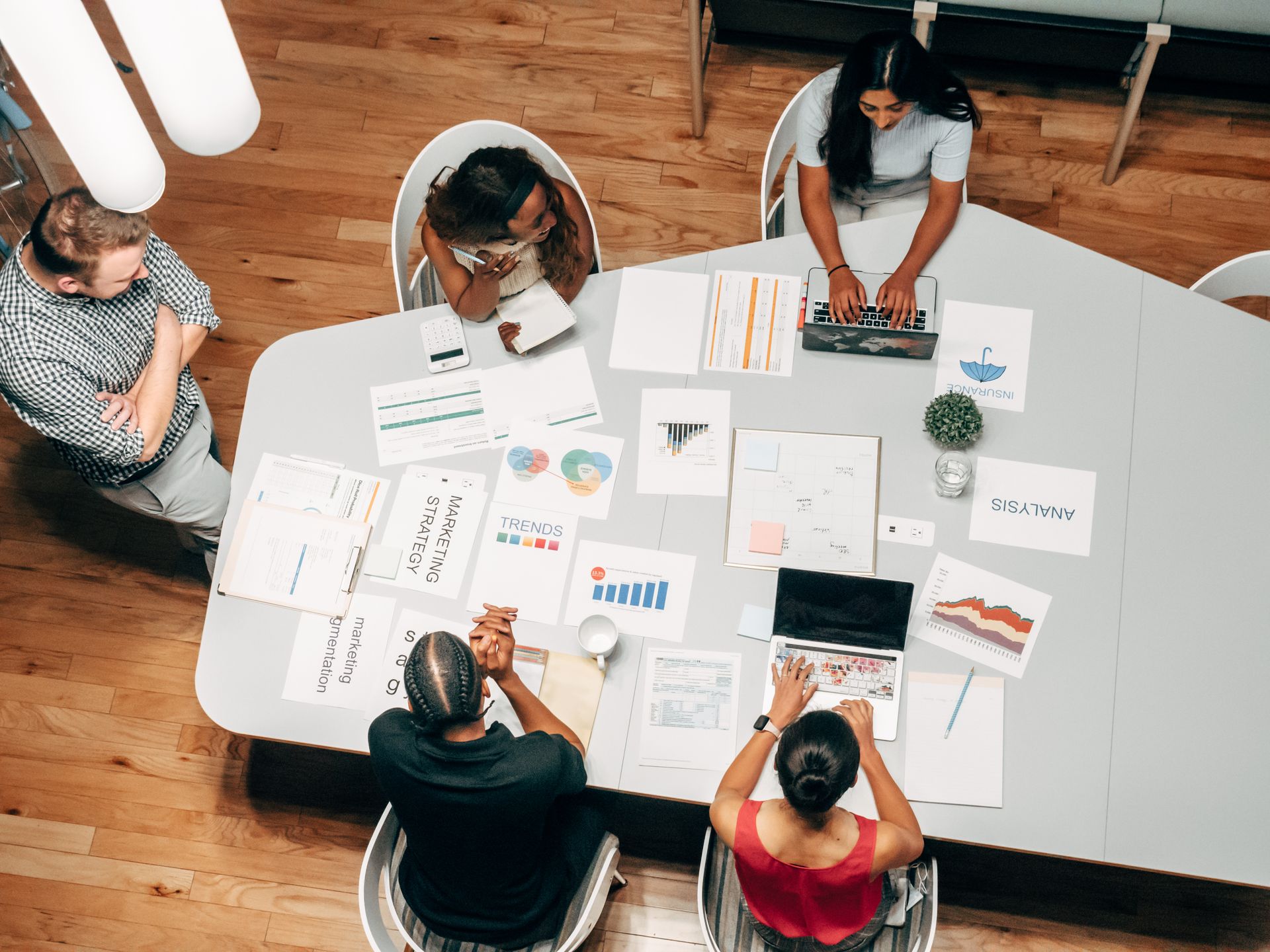Hombres y mujeres jóvenes de distintos fenotipos colaborando en una mesa de trabajo